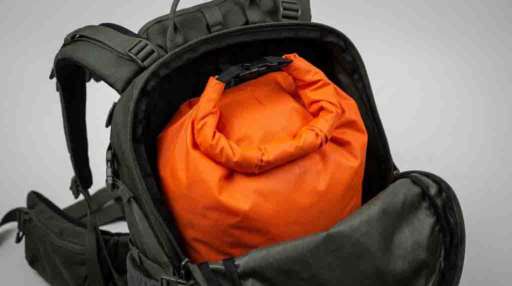 A roll-top dry bag used as a waterproof liner inside a backpack's main compartment